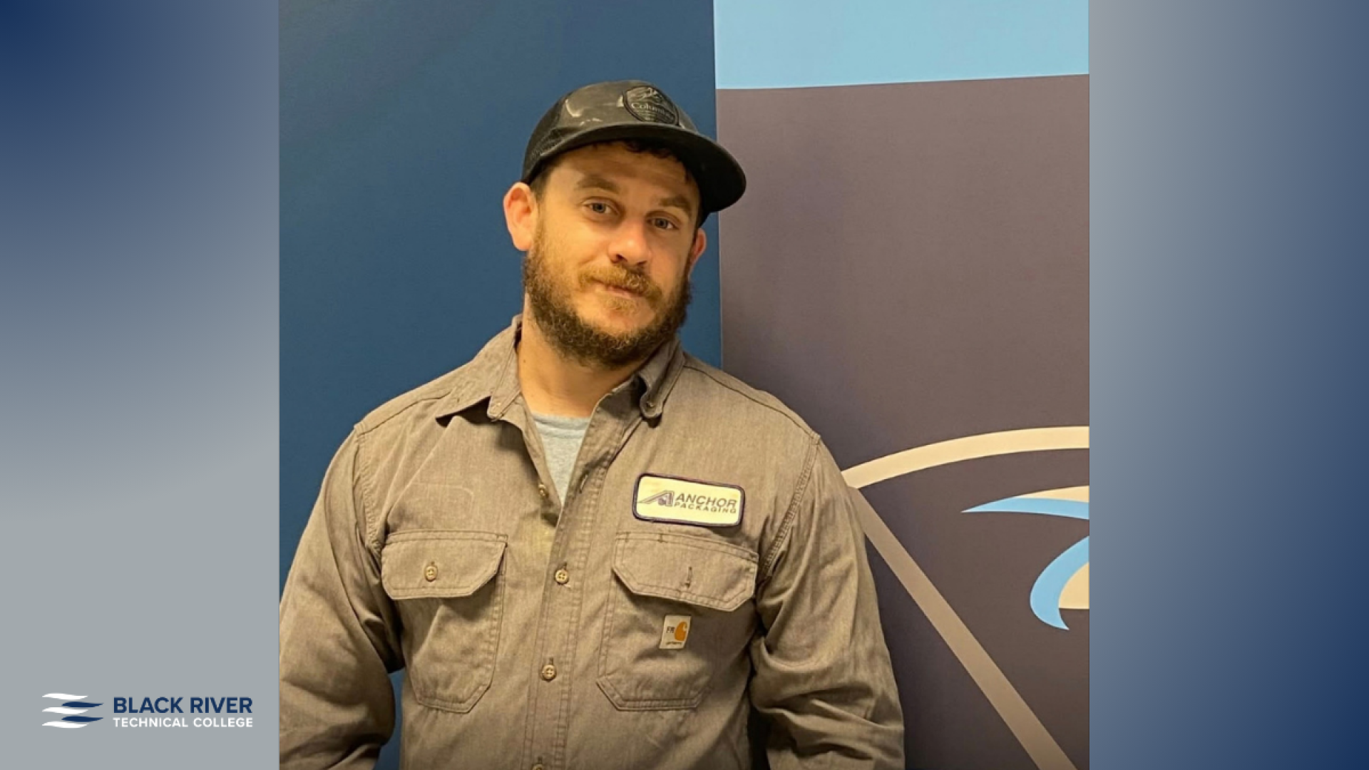 A bearded man wearing a cap and a gray work shirt with an Anchor Packaging patch stands in front of a blue and gray backdrop, with Black River Technical College branding.